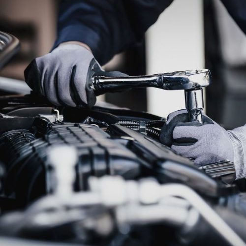 Professional mechanic working on the engine of the car in the garage.